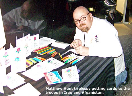 Matthew Hunt writing letters to troops in Iraq at the GBK Gift Suite