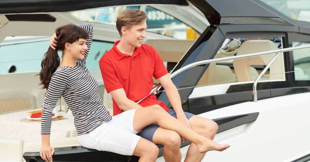 A happy and young couple enjoying sitting on their boat while looking out into the water on a sunny day.