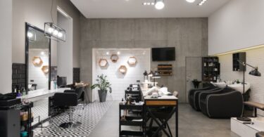 The interior of a modern-looking salon. There are hair and nail stations, all with a lot of equipment sitting out, ready to use.