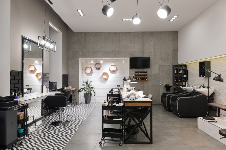 The interior of a modern-looking salon. There are hair and nail stations, all with a lot of equipment sitting out, ready to use.