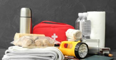 A small collection of emergency supplies, including a first aid kit, a blanket, water bottles, and a flashlight.