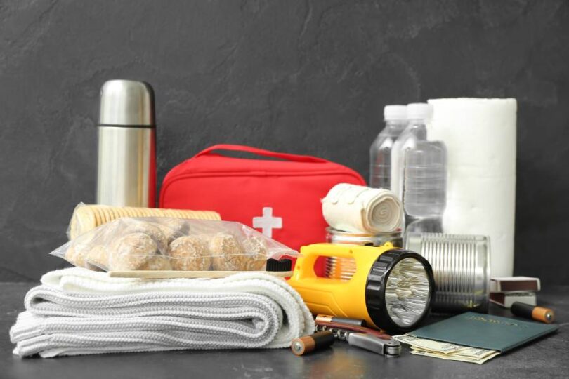 A small collection of emergency supplies, including a first aid kit, a blanket, water bottles, and a flashlight.