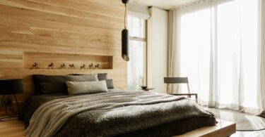 A platform bed built into a wood paneled wall feature. The wall has a cut out shelf with small trinkets on it.