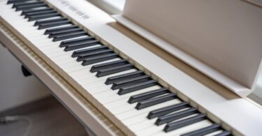 A close-up of a white piano synthesizer with a music tray on its end and sleek white and black keys.