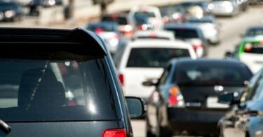 Vehicles fill all lanes during heavy traffic congestion on a freeway near a major city in broad daylight.