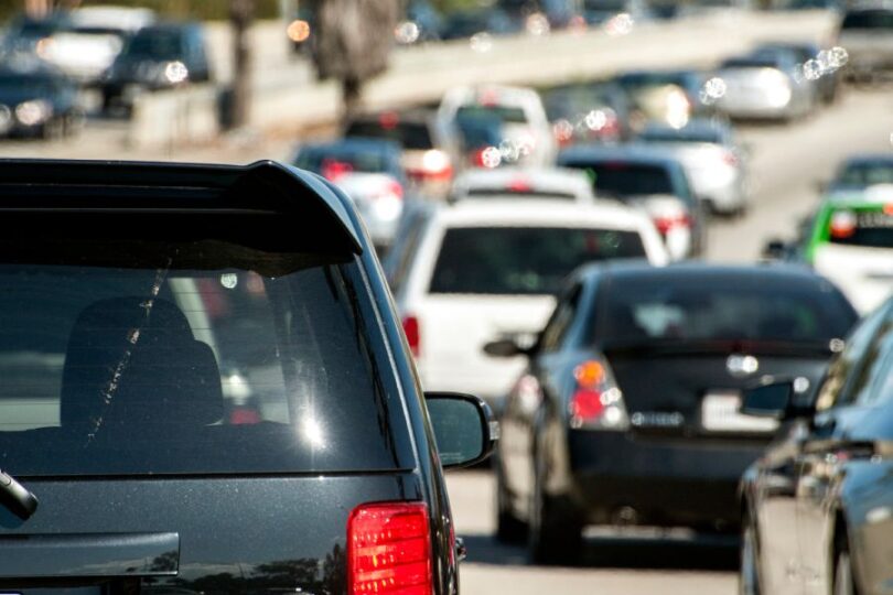Vehicles fill all lanes during heavy traffic congestion on a freeway near a major city in broad daylight.