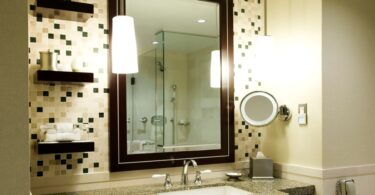 A guest bathroom features a scattered tile backsplash of black, white, and grey tiles. The bathroom is lit with warm light.