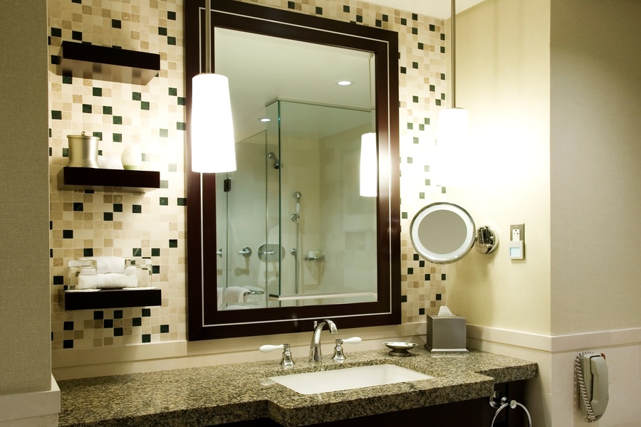A guest bathroom features a scattered tile backsplash of black, white, and grey tiles. The bathroom is lit with warm light.
