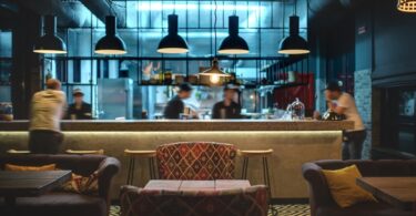 The interior of a restaurant, featuring stylish furniture and a large bar with stylish ambient lighting.