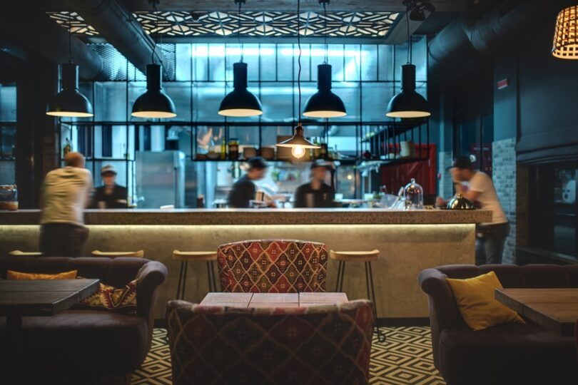 The interior of a restaurant, featuring stylish furniture and a large bar with stylish ambient lighting.