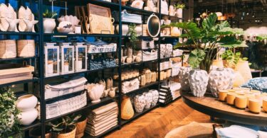 An assortment of decor stacked on shelves in a retail store. There are also items on the table near the shelves.