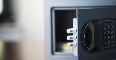 Close-up of open safe with keypad lock and metal bolts extended, showing secure locking mechanism and interior.