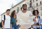 Group of young travelers exploring a city together while smiling and looking at a map during a sightseeing trip