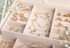 An open jewelry organizer with gold necklaces, rings, and earrings neatly arranged in soft compartments.