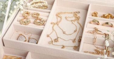 An open jewelry organizer with gold necklaces, rings, and earrings neatly arranged in soft compartments.