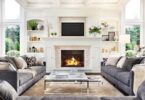 A luxurious living room and fireplace with multiple couches and large windows in the corner of the room.