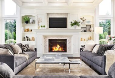A luxurious living room and fireplace with multiple couches and large windows in the corner of the room.