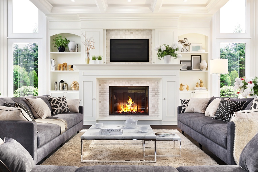 A luxurious living room and fireplace with multiple couches and large windows in the corner of the room.