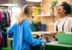 A customer speaks with a smiling employee at the checkout counter of a clothing pop-up shop.