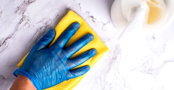 A professional housekeeper carefully cleaning a stone countertop in an upscale Los Angeles home