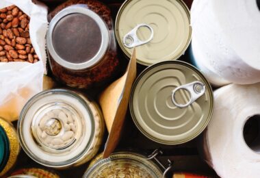 Assorted pantry supplies include canned goods, jars of beans and oats, dried beans, paper towels, and packaged food.